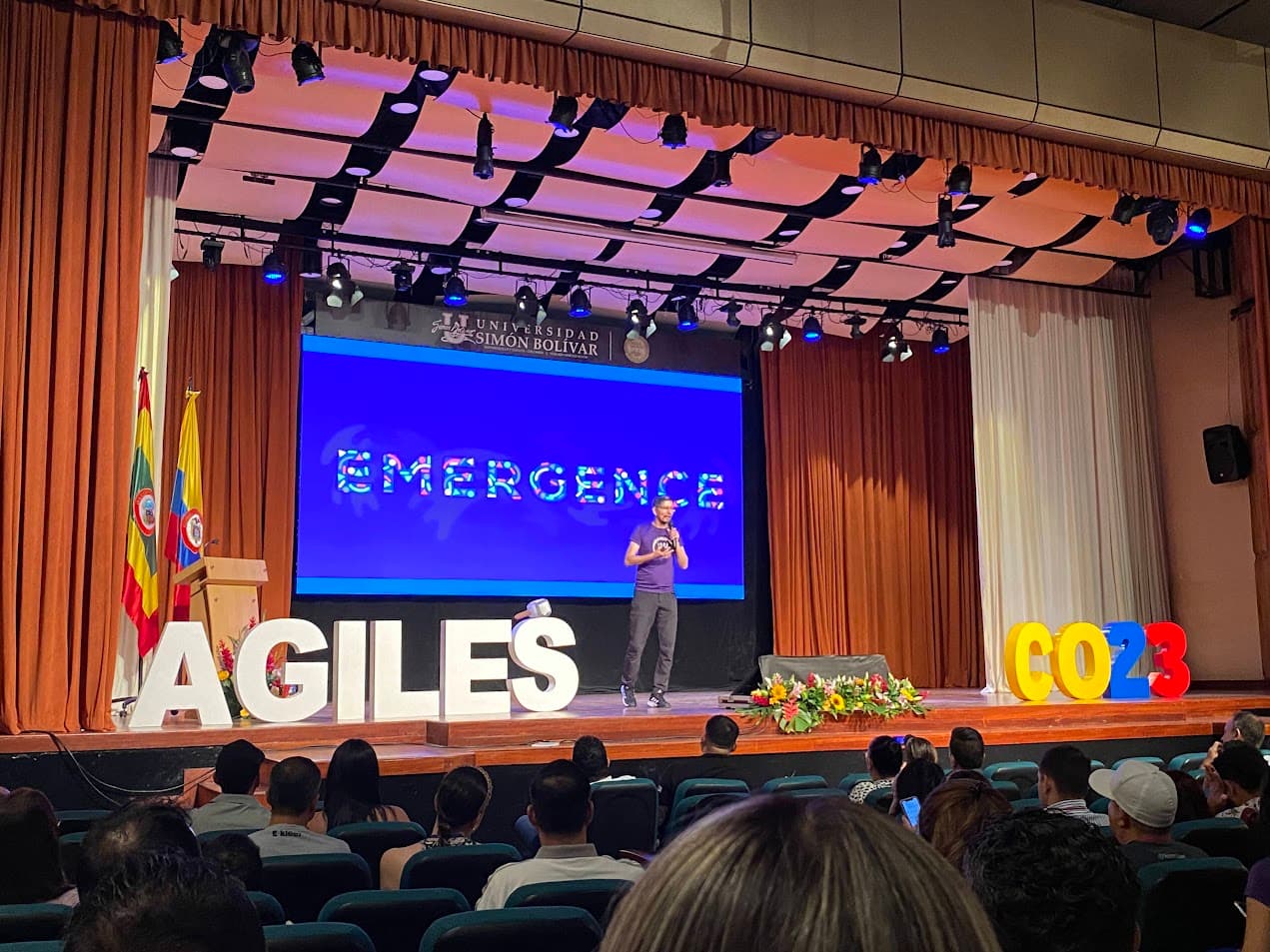 Conferencista en el escenario principal frente al auditorio, con las letras de Ágiles Colombia al frente